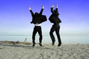 two guys in suits jumping on beach